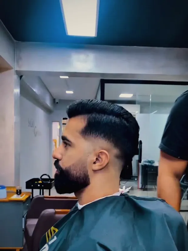 Cliente de perfil com barba alinhada e degradê no Studio Wolver